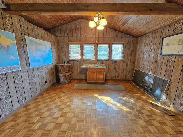 interior space with light parquet floors, lofted ceiling with beams, an inviting chandelier, and wooden walls