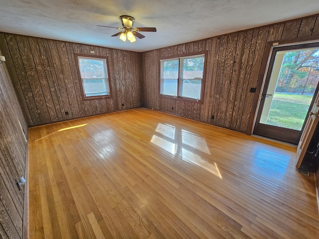 empty room featuring light hardwood / wood-style floors, ceiling fan, and wooden walls