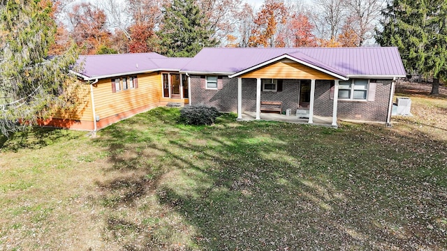 rear view of property featuring a lawn and a patio area