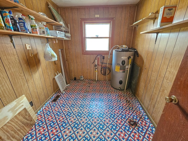 clothes washing area with wood walls and water heater