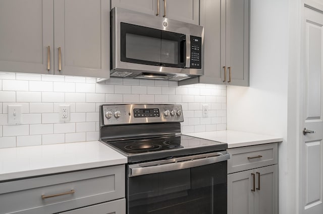 kitchen featuring appliances with stainless steel finishes, backsplash, and gray cabinets