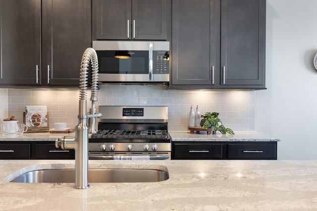 kitchen featuring light stone countertops, dark brown cabinets, decorative backsplash, and sink