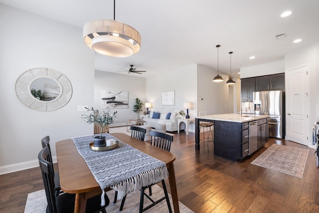 dining space with ceiling fan, sink, and dark wood-type flooring