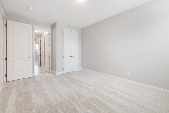 unfurnished bedroom featuring light colored carpet and a closet