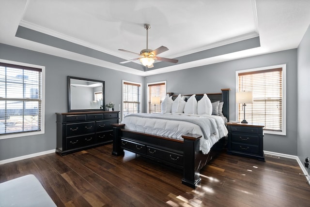 bedroom featuring a tray ceiling, multiple windows, ceiling fan, and dark hardwood / wood-style floors