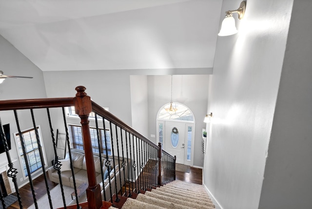 staircase featuring wood-type flooring, high vaulted ceiling, ceiling fan, and a healthy amount of sunlight