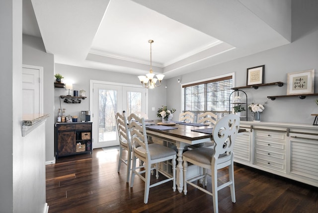 dining area with a tray ceiling, french doors, dark wood-type flooring, and an inviting chandelier