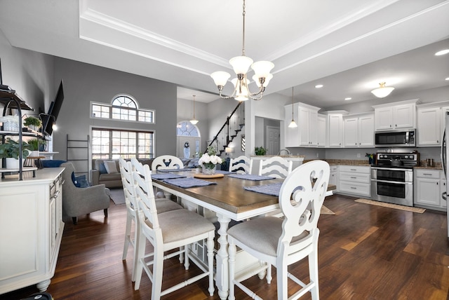 dining space with a tray ceiling, dark hardwood / wood-style flooring, and a chandelier