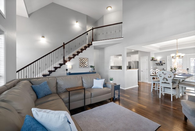 living room featuring dark wood-type flooring, a high ceiling, and an inviting chandelier