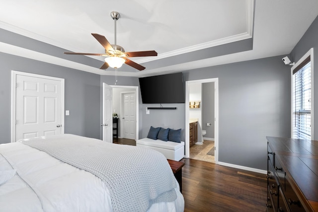 bedroom with ceiling fan, dark hardwood / wood-style flooring, crown molding, ensuite bathroom, and a tray ceiling