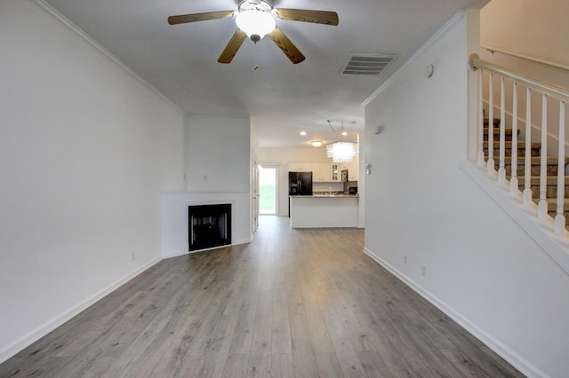 unfurnished living room with ceiling fan, wood-type flooring, and ornamental molding