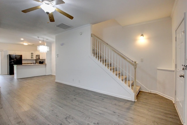 unfurnished living room featuring hardwood / wood-style flooring, ceiling fan, and crown molding