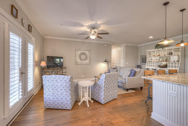 living room with wood-type flooring, ceiling fan, and crown molding