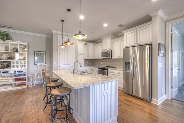 kitchen with light stone countertops, sink, stainless steel appliances, light hardwood / wood-style flooring, and decorative light fixtures