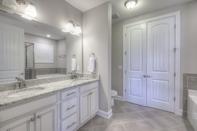 bathroom with tile patterned flooring, vanity, toilet, and a bathing tub