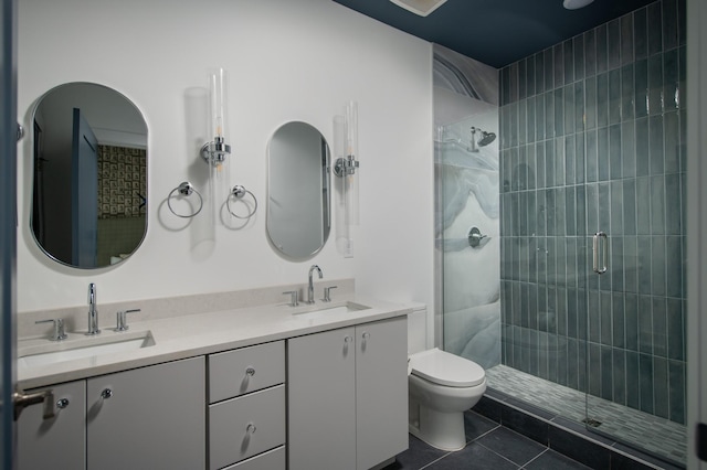 bathroom featuring tile patterned floors, vanity, a shower with shower door, and toilet