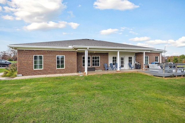 rear view of house featuring a wooden deck, a patio area, and a yard