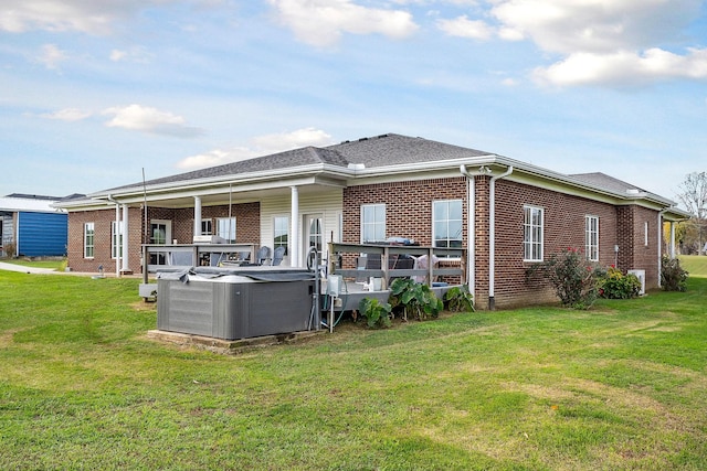 back of property with a yard and a hot tub