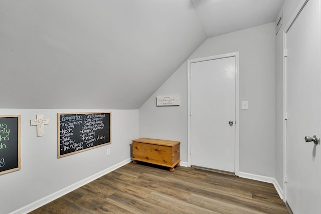 additional living space with hardwood / wood-style flooring and vaulted ceiling