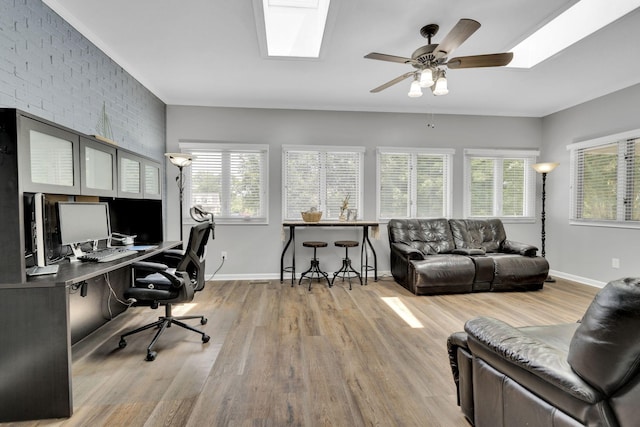 office area with light hardwood / wood-style floors, ceiling fan, and brick wall