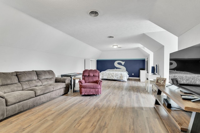 bedroom featuring hardwood / wood-style floors, a textured ceiling, and lofted ceiling