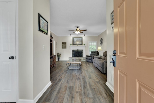 living room featuring a fireplace, dark hardwood / wood-style flooring, ceiling fan, and ornamental molding