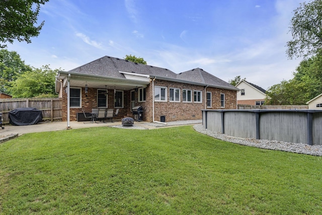 back of property with a patio area, a yard, and a fenced in pool