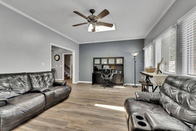 living room featuring hardwood / wood-style flooring, ceiling fan, crown molding, and brick wall