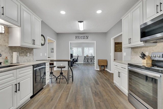 kitchen featuring light stone countertops, appliances with stainless steel finishes, hardwood / wood-style flooring, and white cabinetry