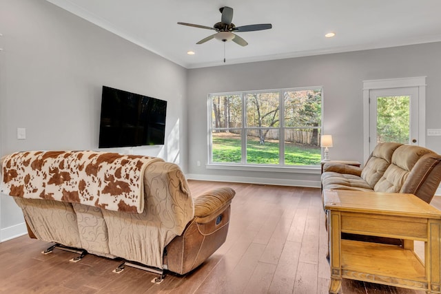 living room with hardwood / wood-style flooring, ceiling fan, and ornamental molding