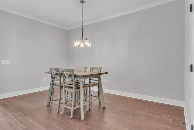 dining area with crown molding, a notable chandelier, and hardwood / wood-style flooring