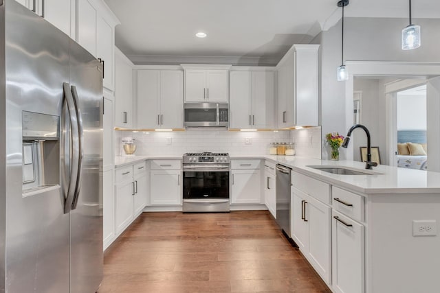 kitchen featuring white cabinetry, sink, stainless steel appliances, and decorative light fixtures