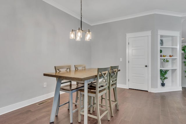 dining room with dark hardwood / wood-style floors, ornamental molding, and a chandelier