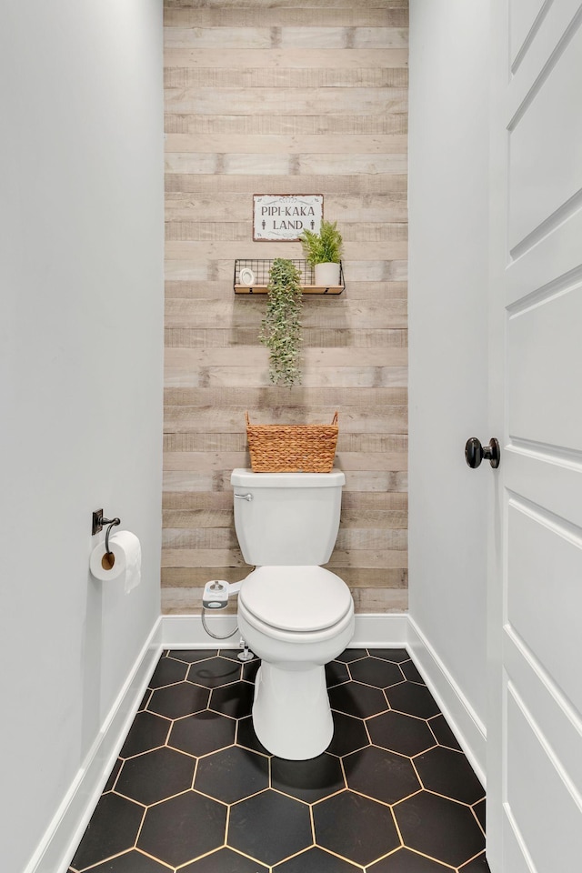 bathroom featuring tile patterned floors, toilet, and wood walls