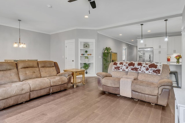 living room featuring ornamental molding, ceiling fan with notable chandelier, and light wood-type flooring