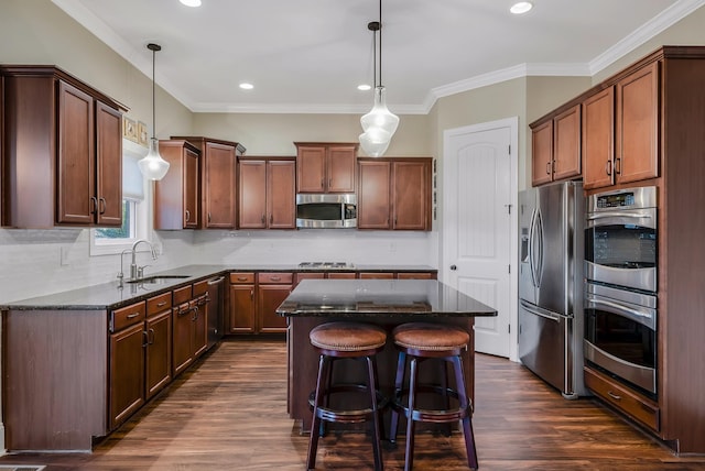 kitchen with sink, a center island, pendant lighting, and appliances with stainless steel finishes