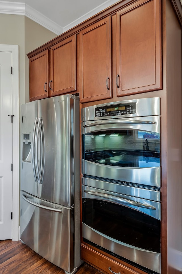 kitchen featuring appliances with stainless steel finishes, ornamental molding, and dark wood-type flooring