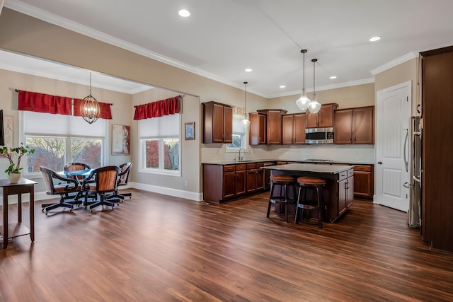 kitchen featuring a center island, sink, stainless steel appliances, dark hardwood / wood-style floors, and a kitchen bar