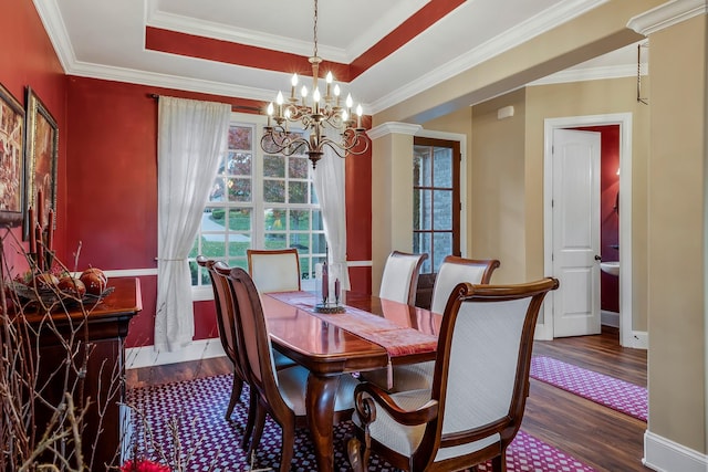 dining space with dark hardwood / wood-style flooring, a tray ceiling, an inviting chandelier, and ornamental molding