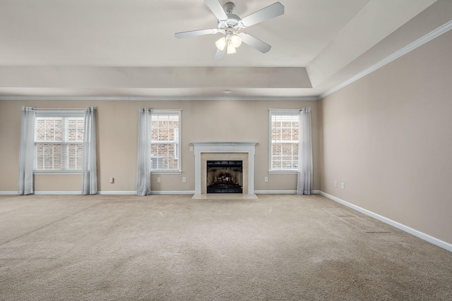 unfurnished living room featuring ceiling fan, light colored carpet, crown molding, and a tray ceiling