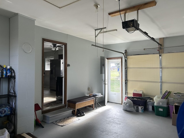 garage with ceiling fan, electric panel, black fridge, and a garage door opener