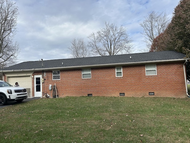 back of property with a garage and a lawn