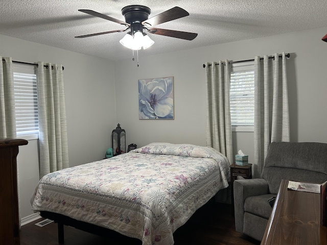 bedroom with ceiling fan, dark hardwood / wood-style flooring, a textured ceiling, and multiple windows