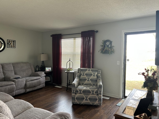 living room with dark hardwood / wood-style floors, a healthy amount of sunlight, and a textured ceiling