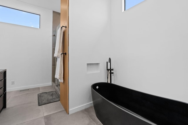 bathroom with tile patterned floors, a wealth of natural light, vanity, and a bath