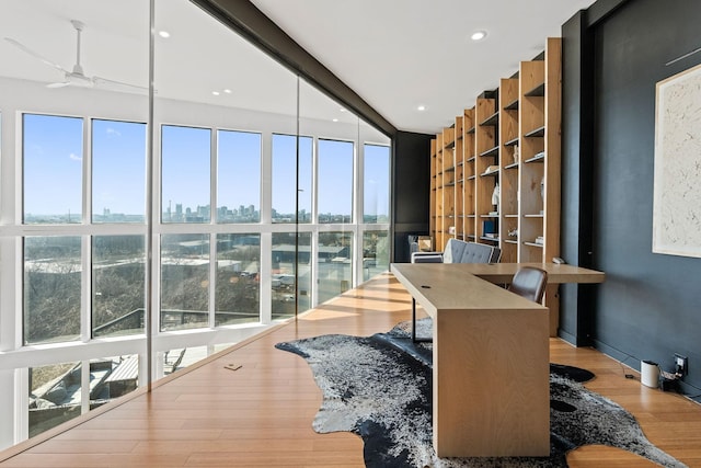 office space with wood-type flooring, expansive windows, and ceiling fan