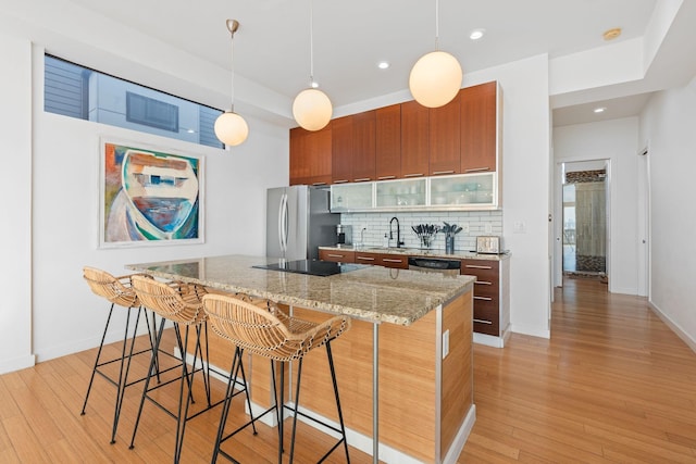 kitchen with tasteful backsplash, a kitchen breakfast bar, light wood-type flooring, and appliances with stainless steel finishes