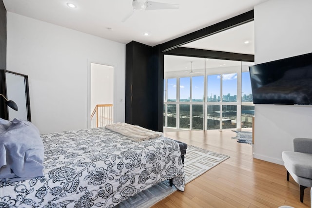 bedroom with beam ceiling, floor to ceiling windows, ceiling fan, and light wood-type flooring