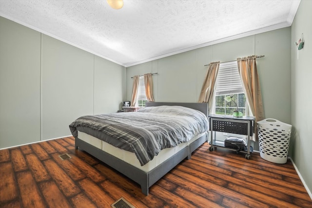 bedroom with crown molding, lofted ceiling, a textured ceiling, and dark wood-type flooring