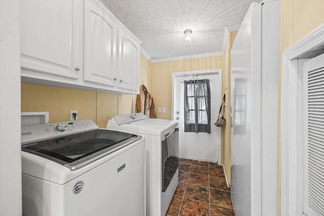 laundry area featuring cabinets, a textured ceiling, washing machine and dryer, and crown molding